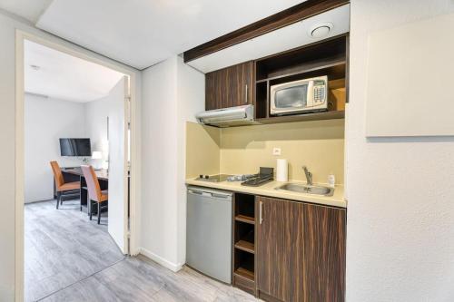 une petite cuisine avec un évier et un micro-ondes dans l'établissement ZenBNB / CityZen / Pied du TRAM / Frontière Suisse, à Gaillard