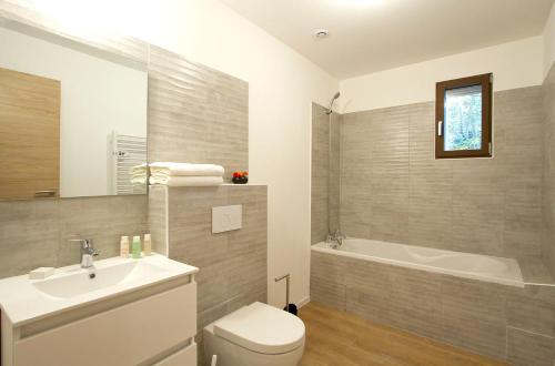 a bathroom with a sink and a tub and a toilet at Résidence Provençal by Leavetown Vacations in Les Deux Alpes