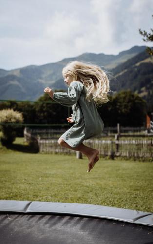 a young girl jumping in the air on a trampoline at Biohof Ebengut in Maria Alm am Steinernen Meer