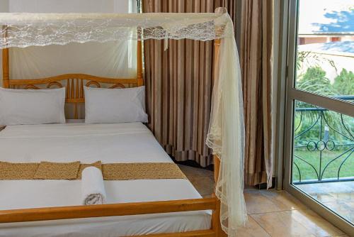 a bedroom with two beds and a balcony at Garden Courts Hotel Masaka in Masaka