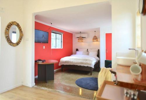 1 dormitorio con paredes rojas, 1 cama y lavamanos en Bulimba Studio en Brisbane