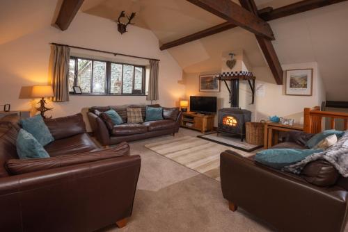 uma sala de estar com mobiliário de couro e uma lareira em The Coach House, Skelwith Bridge em Grasmere
