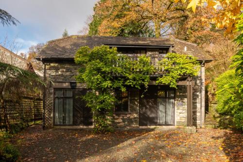 a stone house with a tree in front of it at The Coach House, Skelwith Bridge in Grasmere