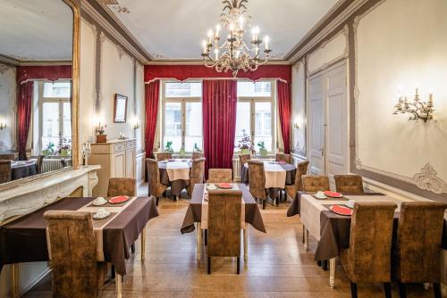 a restaurant with tables and chairs and a chandelier at Hotel Van Eyck in Bruges