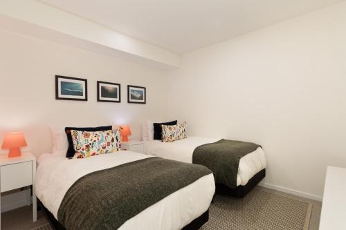 two beds in a room with white walls at Hearthstone Lodge 8 - Heart of Village, Hot Tub, Wood-Burning Fireplace - Whistler Platinum in Whistler
