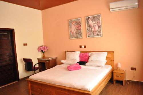 a bedroom with a bed with white sheets and pink pillows at Santa Monica Home Lodge in Senchi