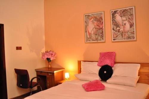 a bedroom with a bed with pink pillows on it at Santa Monica Home Lodge in Senchi