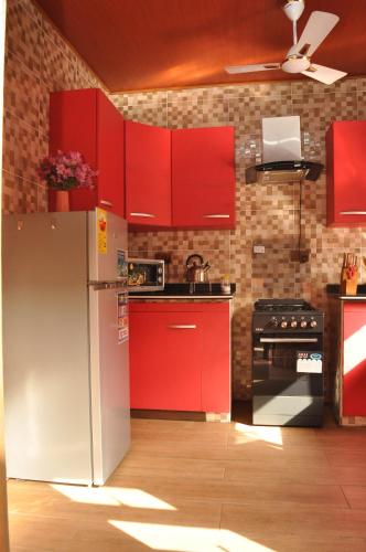 a kitchen with red cabinets and a refrigerator at Santa Monica Home Lodge in Senchi