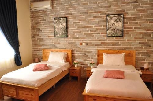 two beds in a room with a brick wall at Santa Monica Home Lodge in Senchi