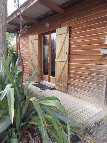 - un bâtiment en bois avec des portes et une terrasse couverte dans l'établissement Le petit chalet, à Chanas