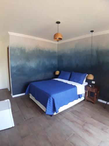 um quarto com uma cama e uma parede azul em Good Vibes em Ilhabela