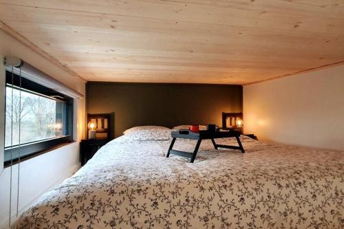 Un dormitorio con una cama grande y una mesa. en Tiny House nature proche Montargis - 1h de Paris !, 