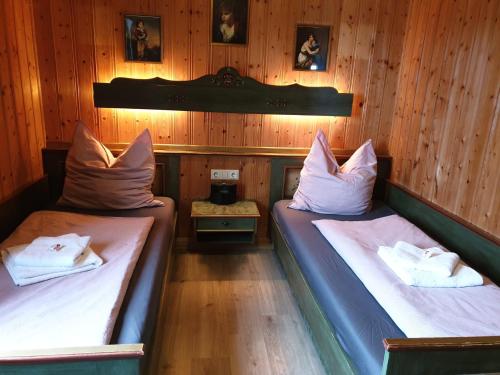 two twin beds in a room with wooden walls at Urig mitten im Bayerischen Wald mit traumhaften Fernblick WLAN kostenfrei in Schöfweg