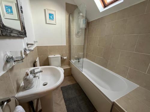 La salle de bains est pourvue d'un lavabo, d'une baignoire et de toilettes. dans l'établissement Scenic 2 bedroom Cottage, à Hill Top