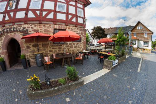 a restaurant with tables and red umbrellas on a street at Ratskeller Niederurff - Hotel & Restaurant in Bad Zwesten