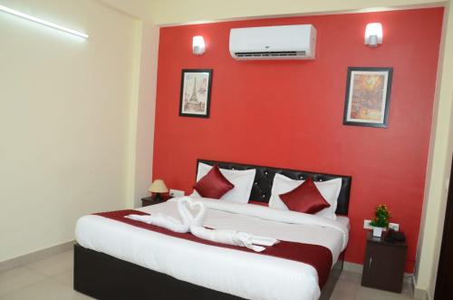 een slaapkamer met een rode muur en een bed bij Rumaisa Red in Noida