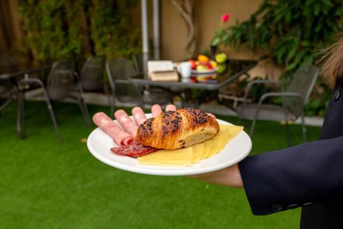 a person holding a plate with a sandwich and chips at Europe Hotel in Sofia
