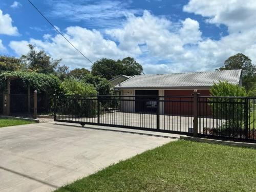 a black fence in front of a house at Gardens by the Bay - Acreage Living & EV Charging in Deception Bay