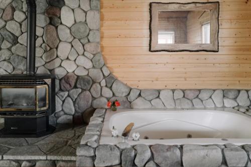eine Badewanne in einem Zimmer mit einer Steinmauer in der Unterkunft 2401 - Oak Knoll Studio with Jacuzzi #2 cabin in Big Bear Lake