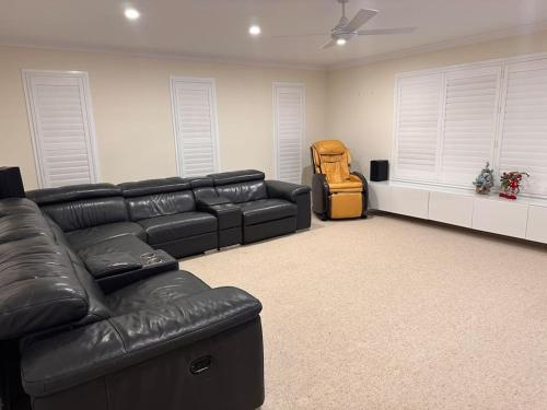 a living room with a black leather couch and a chair at Gardens by the Bay - Acreage Living & EV Charging in Deception Bay