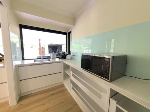 a kitchen with a counter with a microwave and a window at Gardens by the Bay - Acreage Living & EV Charging in Deception Bay