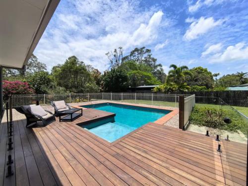 a wooden deck with a swimming pool and a wooden deck at Gardens by the Bay - Acreage Living & EV Charging in Deception Bay