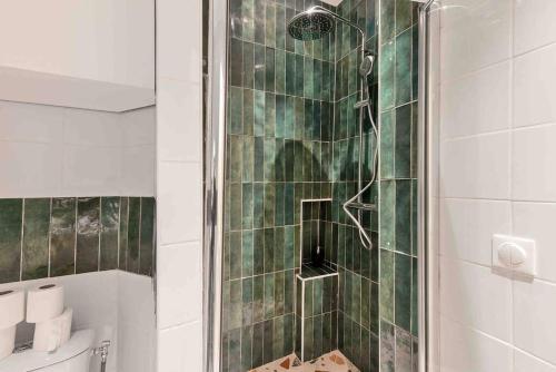 La salle de bains est pourvue d'une douche avec du carrelage vert. dans l'établissement MONTMARTRE, Gare de l'EST, suite 1 chambre 2 à 4P, à Paris