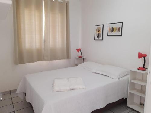 a white bedroom with a bed and a window at Pousada Ingleses Beach in Florianópolis