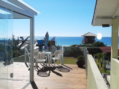 a deck with a table and chairs and the ocean at Pousada Ingleses Beach in Florianópolis