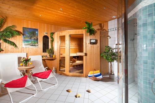um quarto com cadeiras brancas, uma mesa e um tecto de madeira em Pension Rennlehen em Berchtesgaden