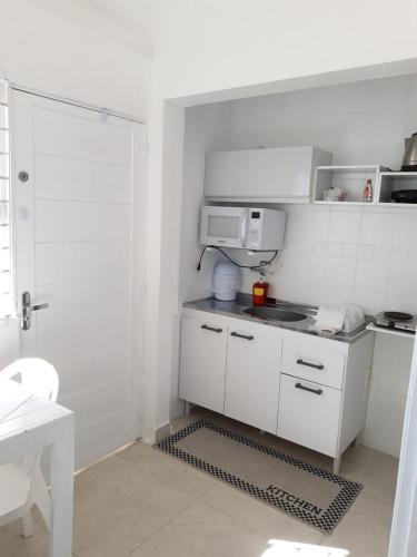 a small white kitchen with a microwave and a stove at Pousada Ingleses Beach in Florianópolis