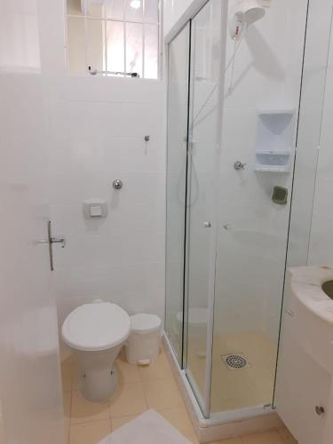 a white bathroom with a shower and a toilet at Pousada Ingleses Beach in Florianópolis