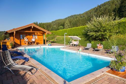 a swimming pool in front of a log cabin at Pension Rennlehen in Berchtesgaden