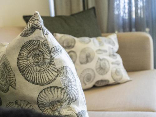 a couch with pillows on it with a blanket at Unit 261 Brookes Hill Suites in Summerstrand