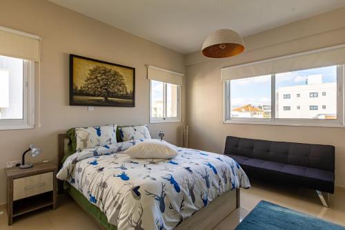een slaapkamer met een bed, een bank en 2 ramen bij Central Bliss / your perfect home away from home in Limassol