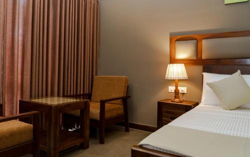 a bedroom with a bed and a chair and a desk at Woodgrove Cabanas in Negombo