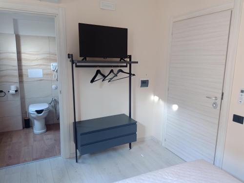 a room with a tv on a stand with a toilet at San Rocco Rooms in Palmi