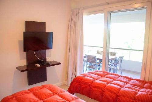 um quarto com uma cama, uma televisão e uma varanda em Solanas Green park resort and spa Vacation Club em Punta del Este