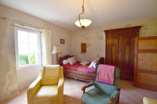 een slaapkamer met een bed en 2 stoelen en een raam bij Ancienne ferme restaurée à Perville, Tarn-et-Garonne in Perville
