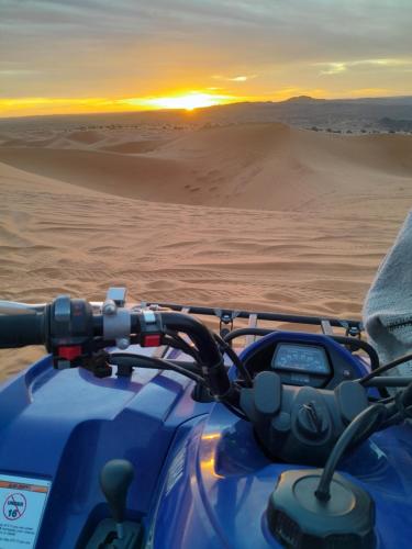a motorcycle in the desert with the sunset in the background at Dunes luxury camp in Merzouga