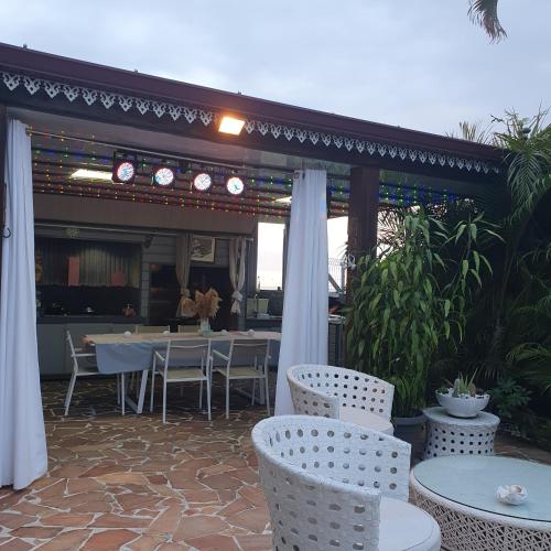 a patio with tables and chairs and a pergola at Sweet metykaz in Le Tampon