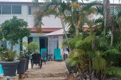 a patio with chairs and palm trees in front of a house at Sweet metykaz in Le Tampon