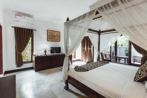 sypialnia z łóżkiem z baldachimem i zasłonami w obiekcie Kishi-Kishi ArtVilla w mieście Blahbatu