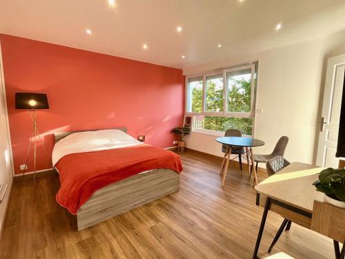 Dormitorio rojo con cama y mesa en Charmant studio + parking privé en Caen