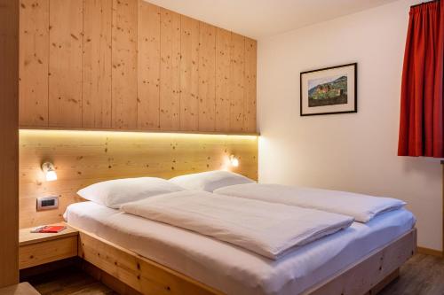 ein Schlafzimmer mit einem großen Bett und einer Holzwand in der Unterkunft Stoffel Apartments Marie in Selva
