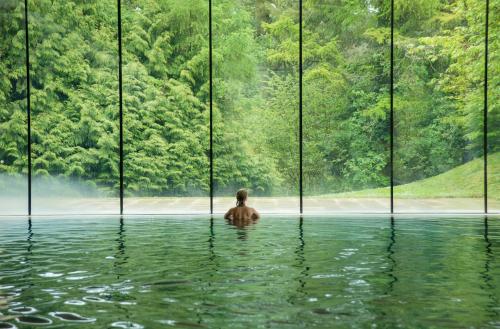 un hombre en un charco de agua frente a una gran ventana en Cowley Manor Experimental, en Cheltenham