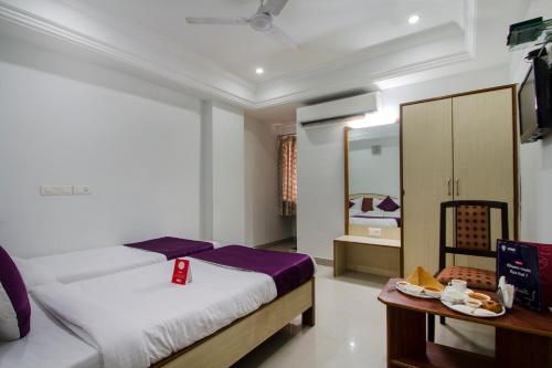 a bedroom with a bed and a table and a tv at Super OYO Flagship Hotel Surya Residency in Ameerpet