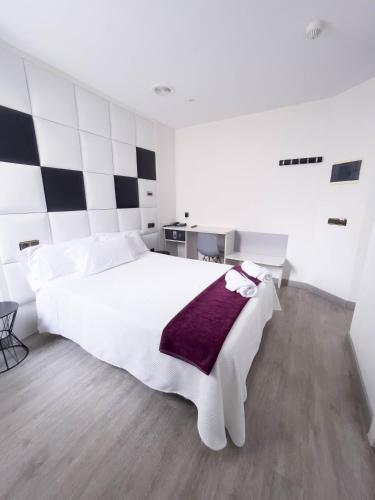 a bedroom with a large white bed with a purple blanket at Hoteles Urbanos N Avenida de España in Fuenlabrada