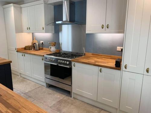 a kitchen with white cabinets and a stove at Beautiful Georgian cottage within a private walled garden in Oakham