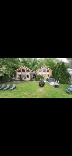 a large house with a yard with benches and chairs at Luxury Lakehouse on Oneida Lake in Blossvale